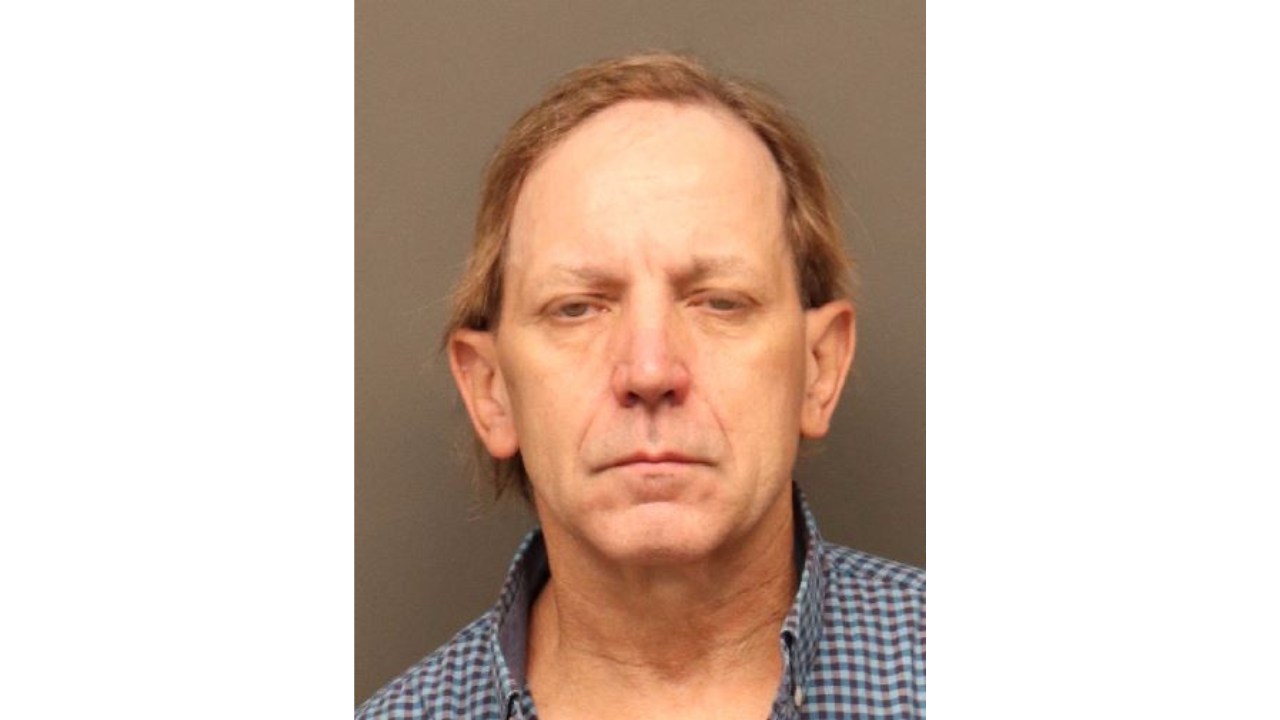 Greg-Buerge.png: Man wearing a checkered shirt, neutral expression, brown background