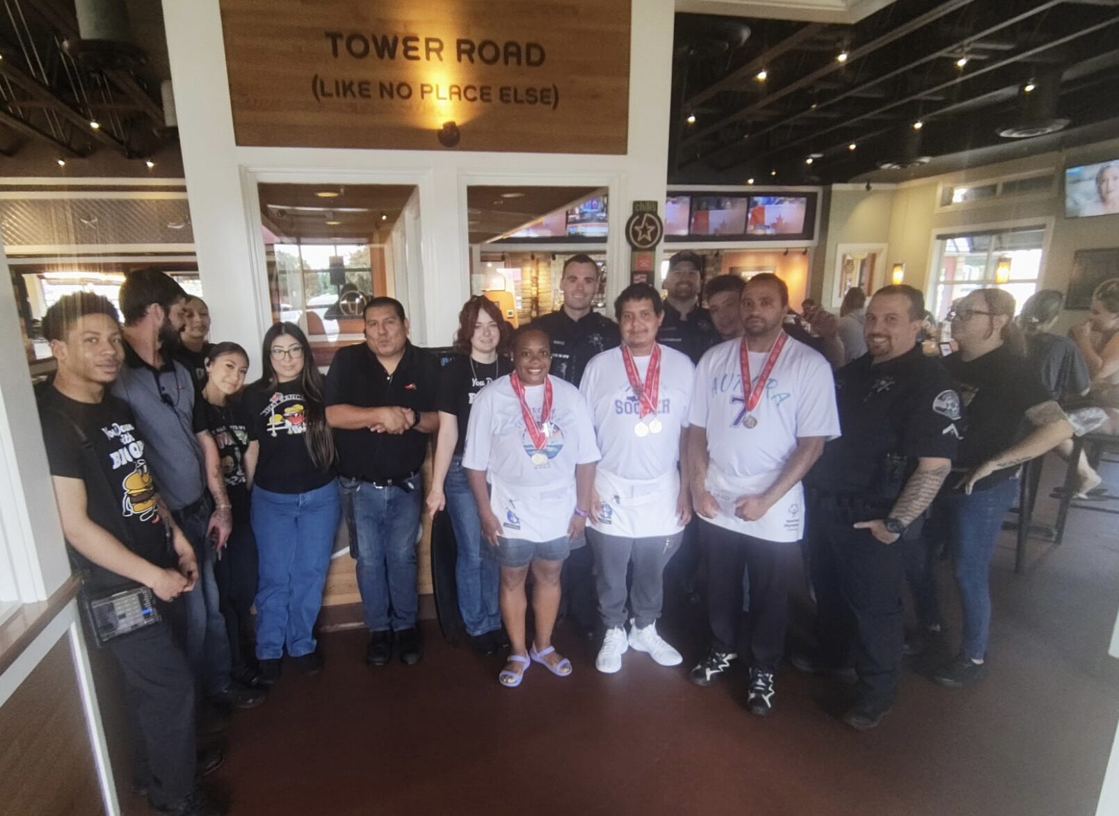 Group photo of law enforcement officers, Chili’s staff, and Special Olympics athletes standing together inside a restaurant during the Tip-A-Cop fundraiser.