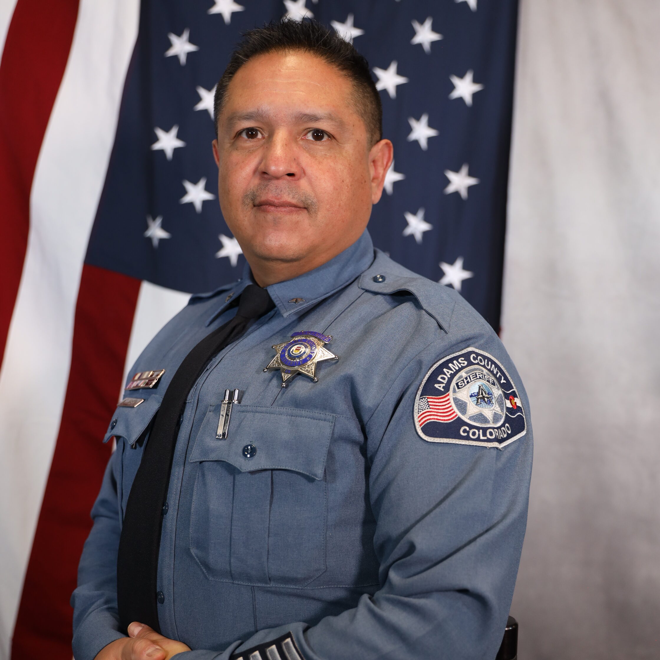 Aragon Manuel in uniform stands before an American flag