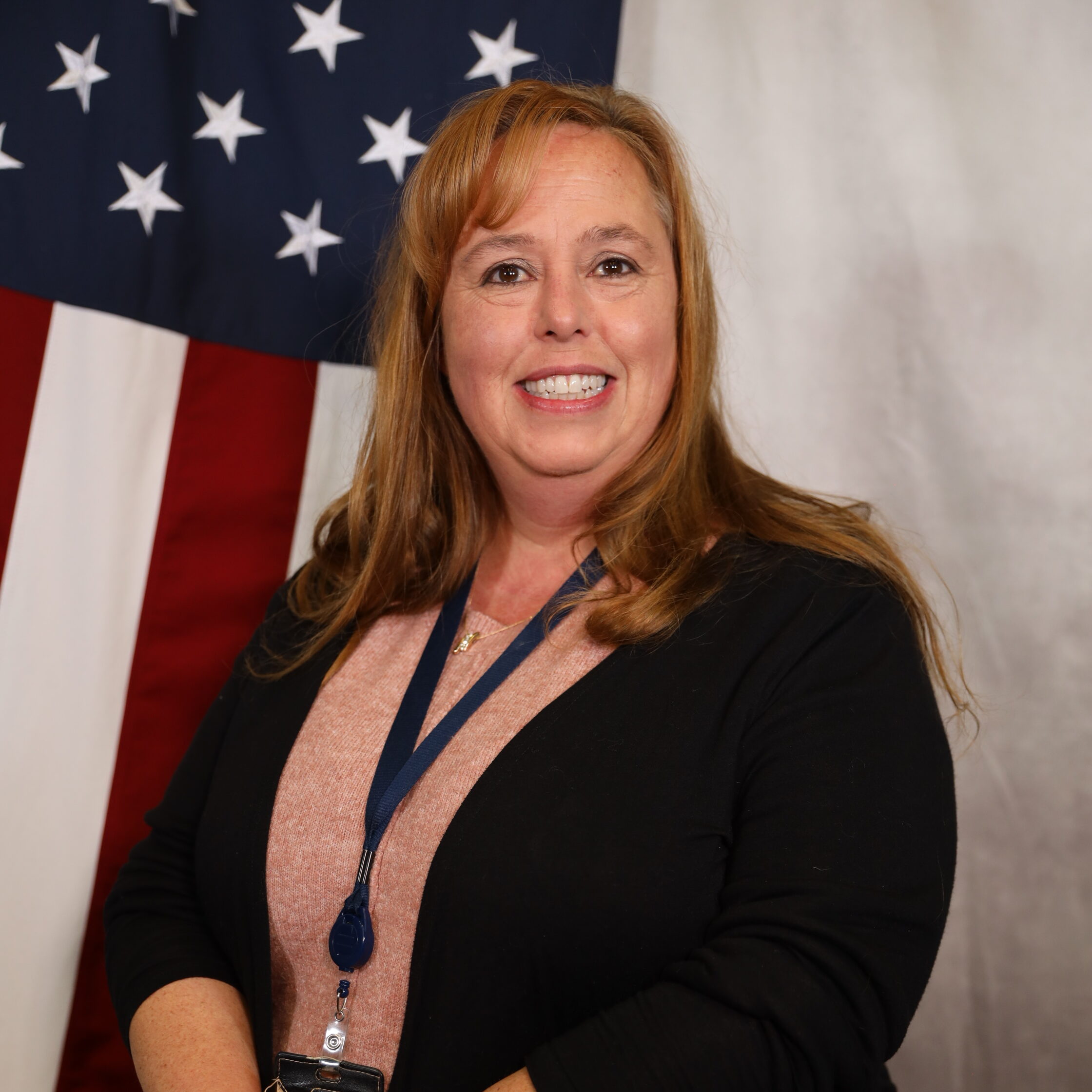 Brandt-Stephanie smiling in front of a U.S. flag backdrop