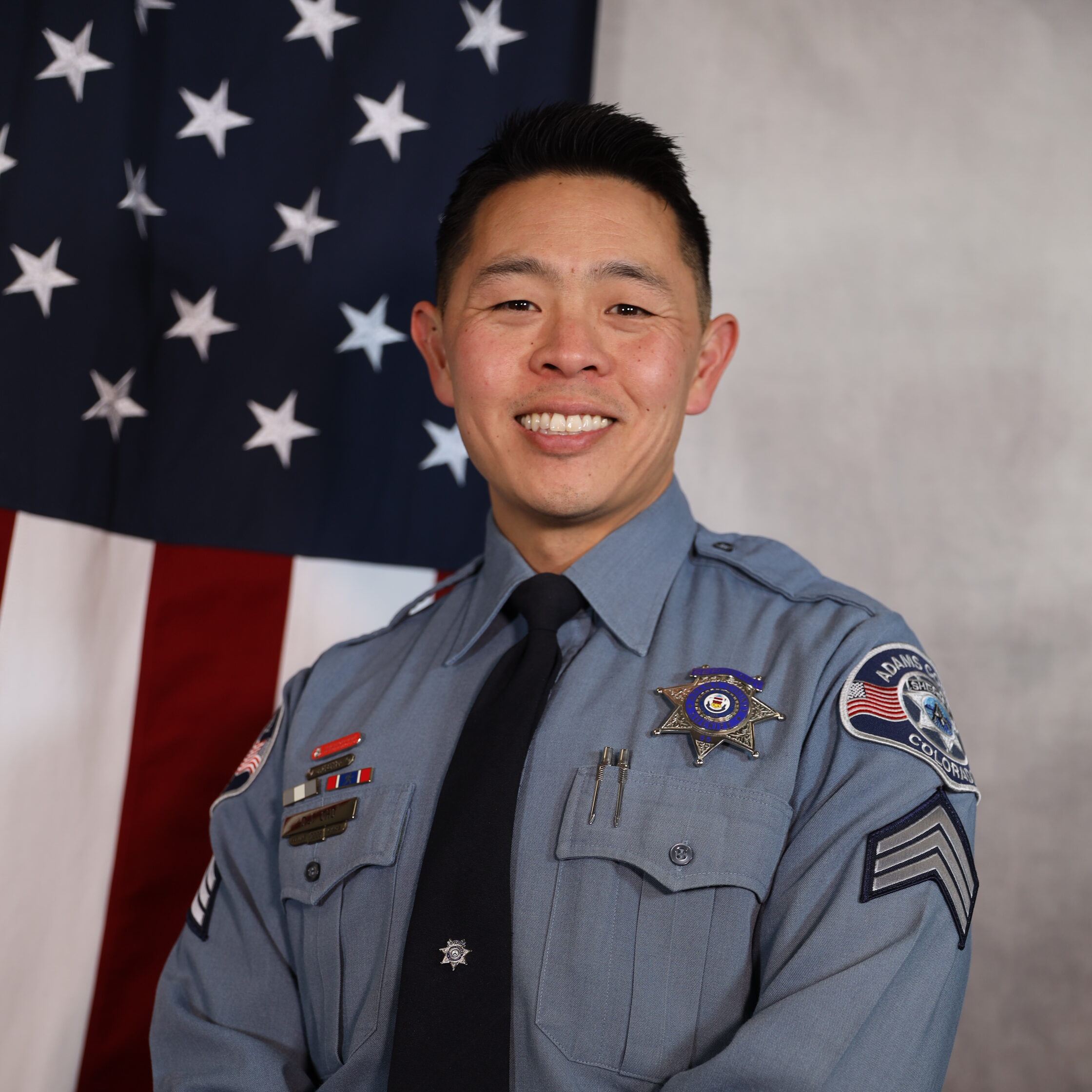 Cho-David.jpg standing in uniform, smiling, with an American flag backdrop