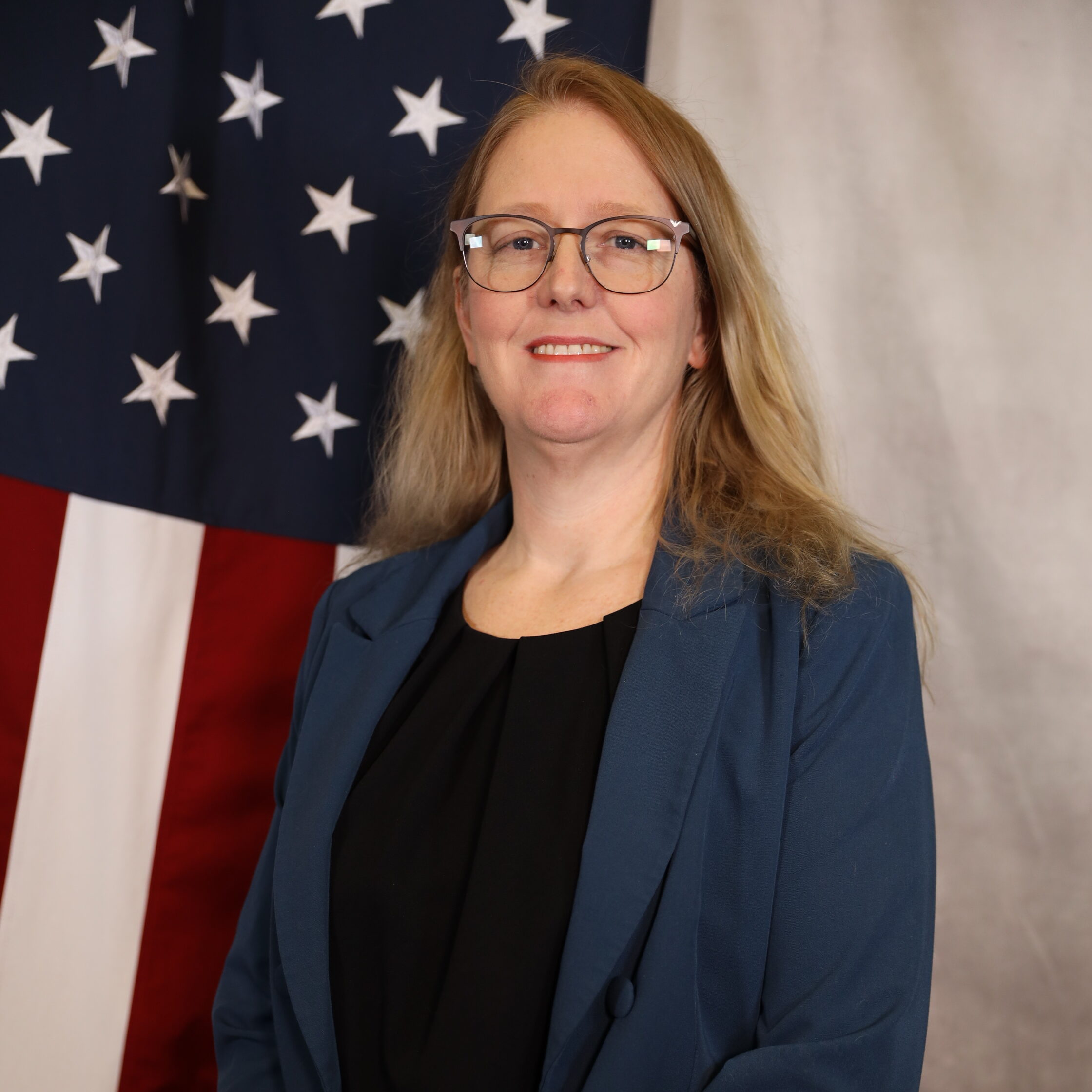 Carrie Haubert smiling in front of an American flag background