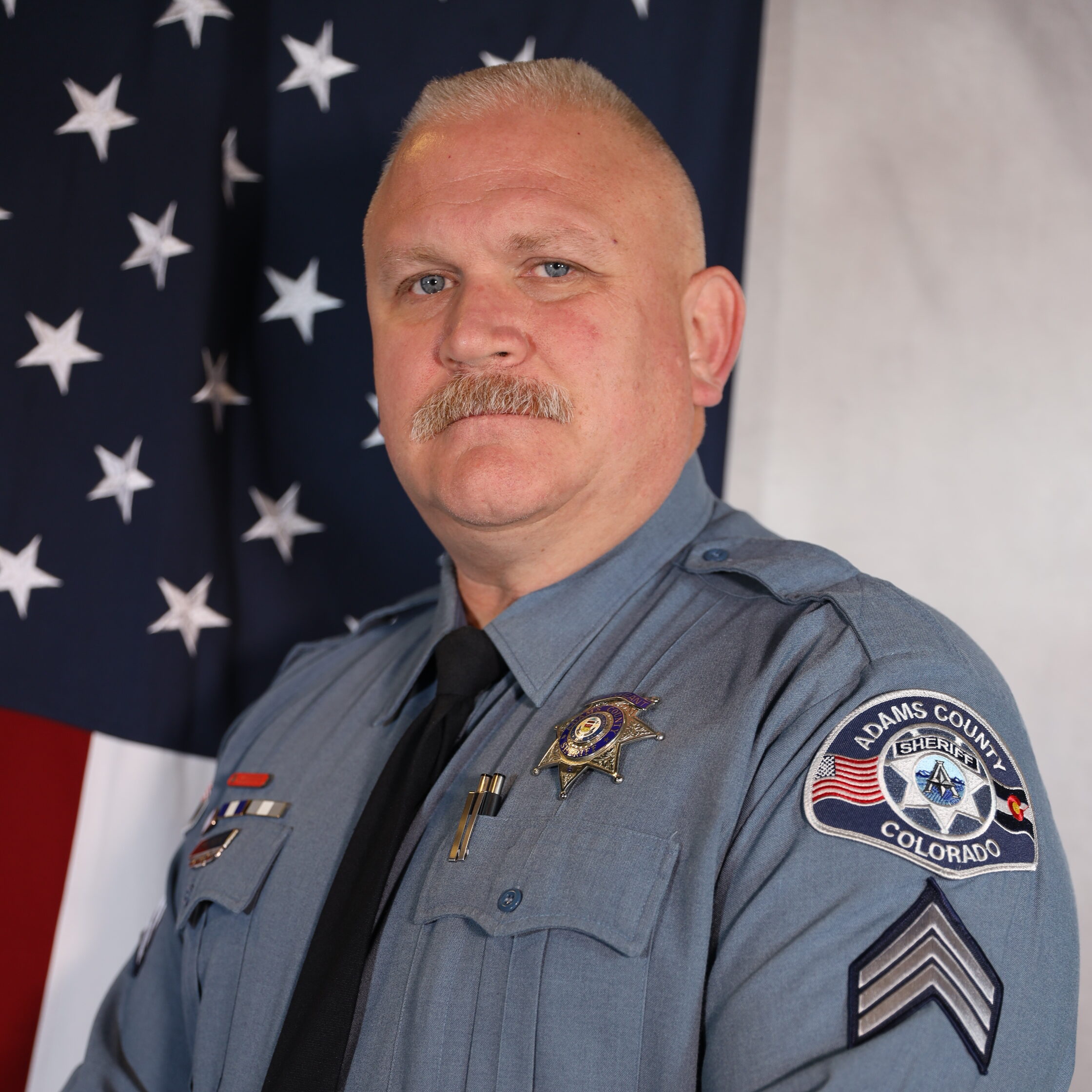 Moore Gabriel in an Adams County Sheriff's uniform stands confidently before an American flag