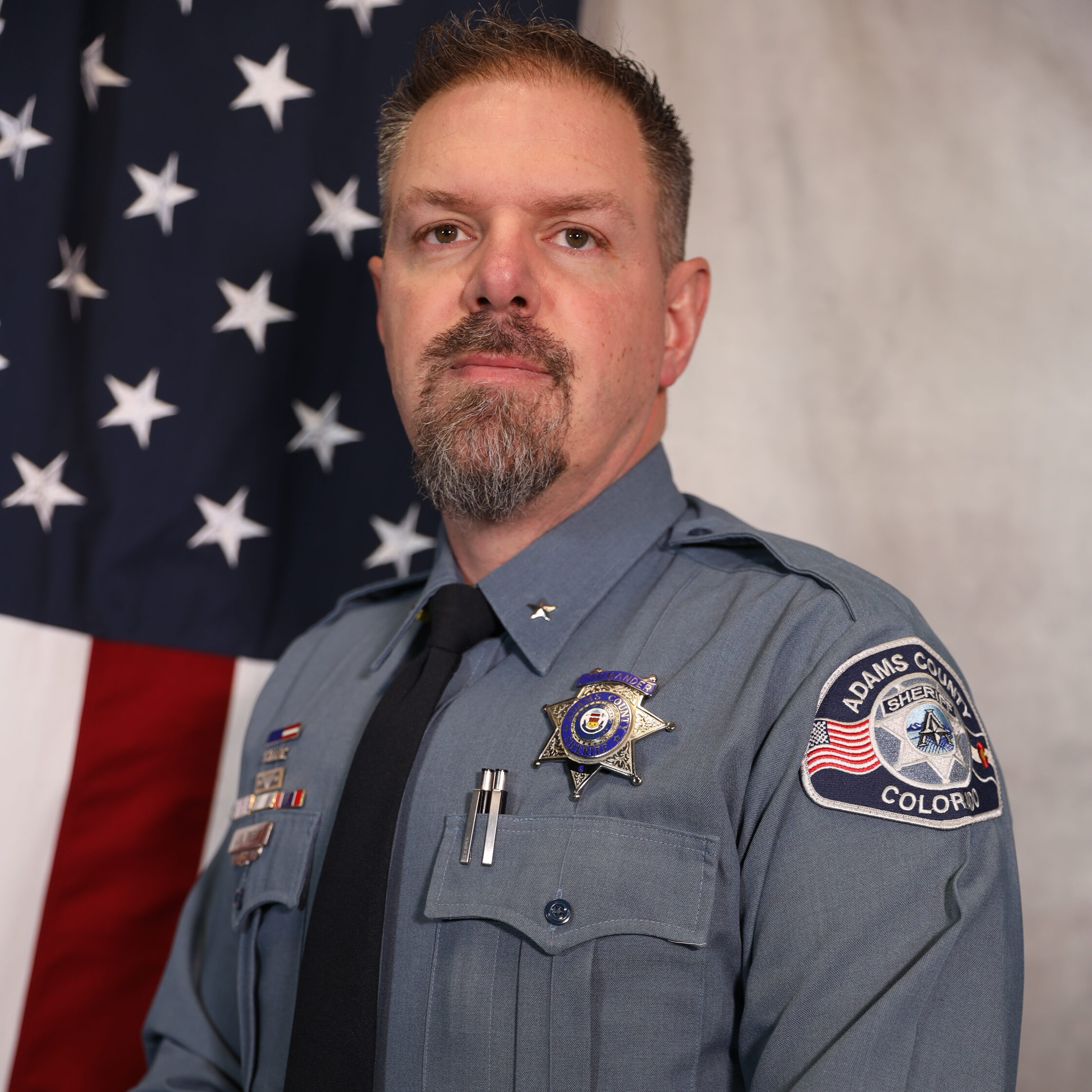 Treblik in uniform against American flag, serious expression